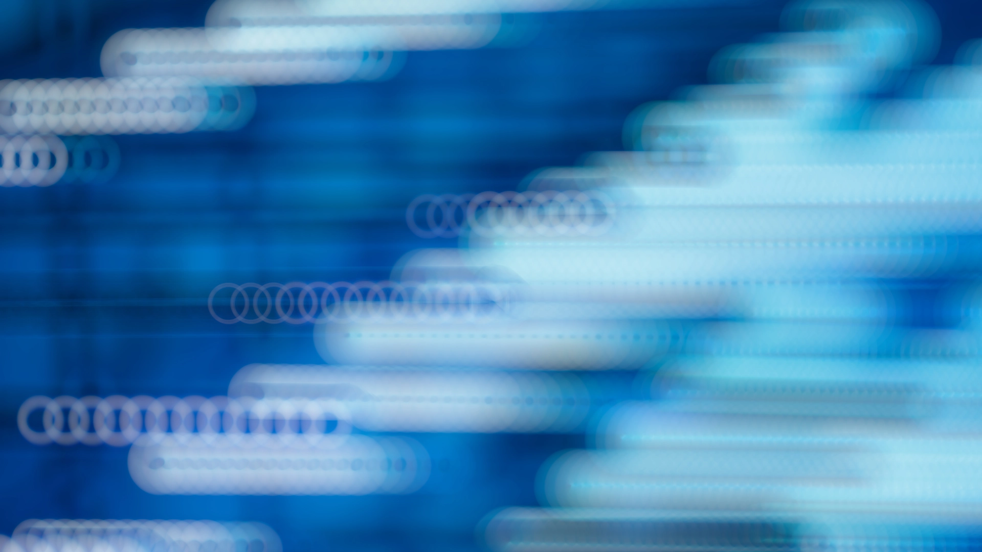 Sfondo astratto blu con scie luminose in movimento che rappresentano la velocità e il flusso di dati tecnologici.